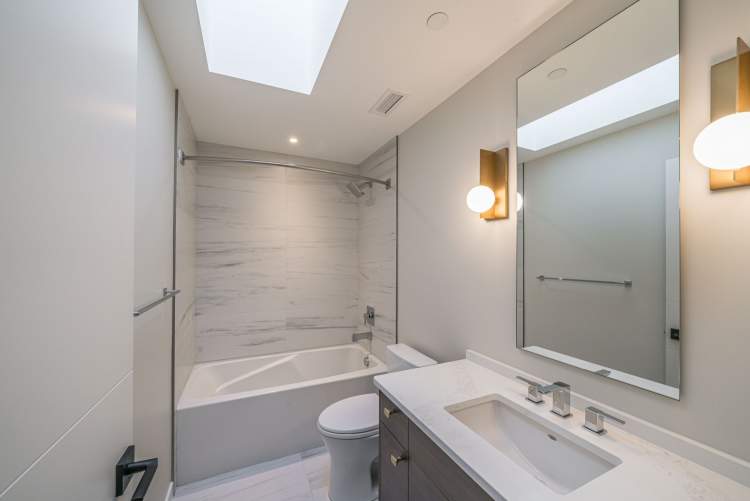 En suites feature white quartz countertops, framless glass shower enclosures, and deep soaker tubs.