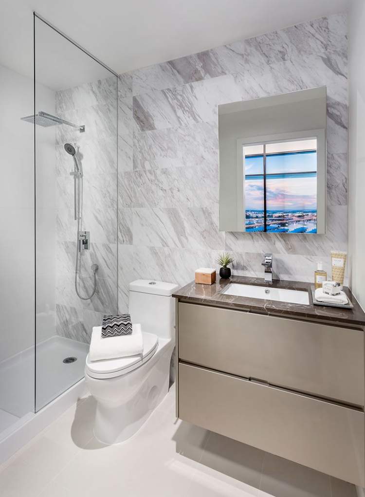 High-gloss cabinetry with elegant marble countertops and mirrored medicine cabinet in en suite.