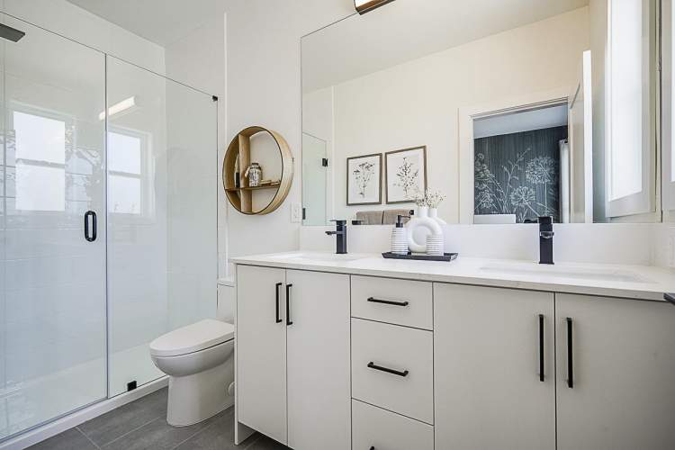 Feature a vanity with two sinks, counter-length mirror, and quartz countertop.