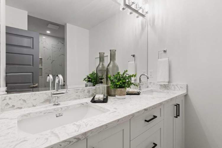 Bathrooms feature Shaker-style vanities with quartz countertops and backsplashes.