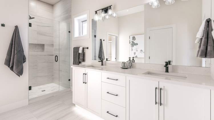 Ensuites present contrasting white cabinetry and matte black plumbing fixtures. 